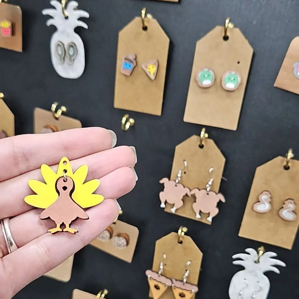 A board of hand-painted wooden earrings, and a turkey pair held up close